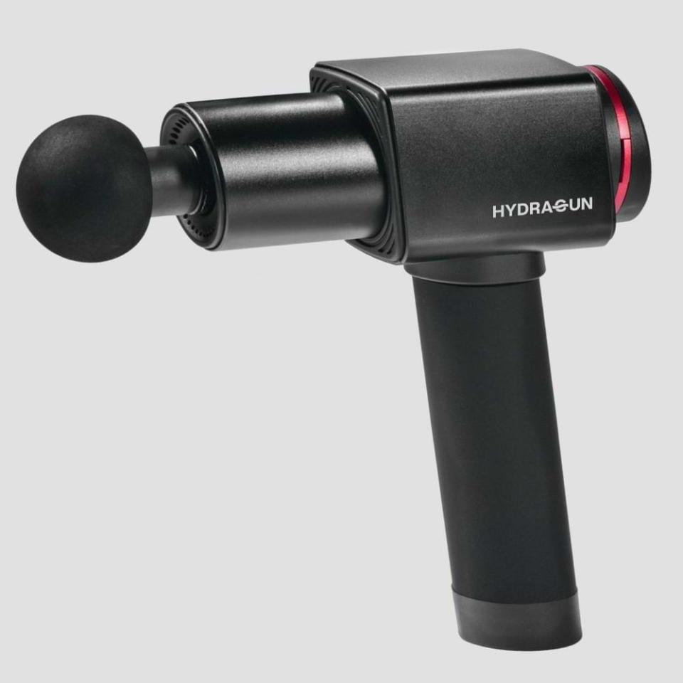 A black Hydragun Massage Gun, $399 shaped like a pistol with a round head and red trim.