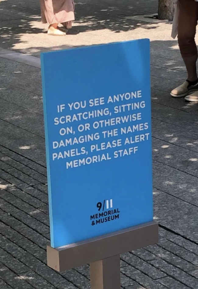 A sign at the 9/11 memorial says "if you see anyone scratching, sitting on, or otherwise damaging the names panels, please alert memorial staff"