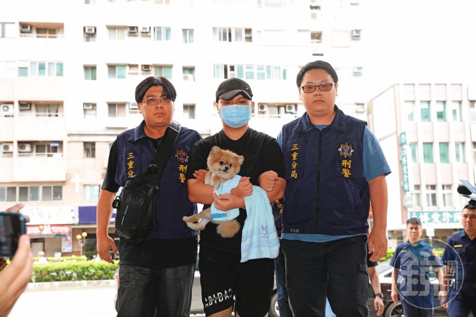 張姓嫌犯（中）被上銬帶回警局，手中還抱著愛犬。