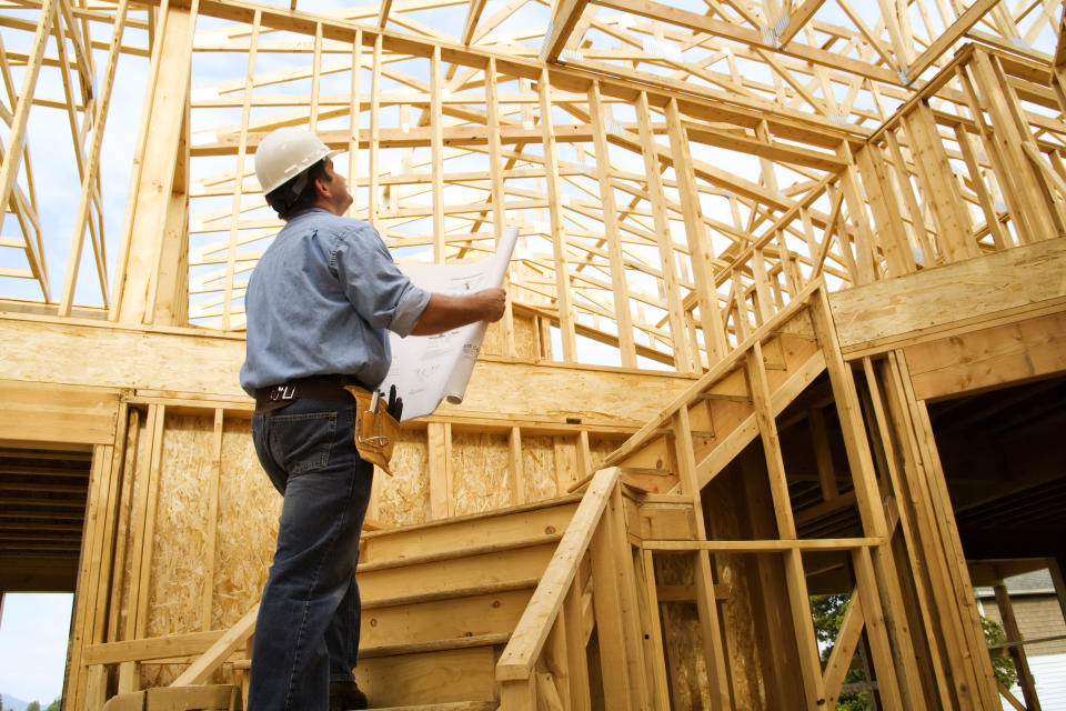 Photo of a construction worker reviewing at set of building plans on the construction site.