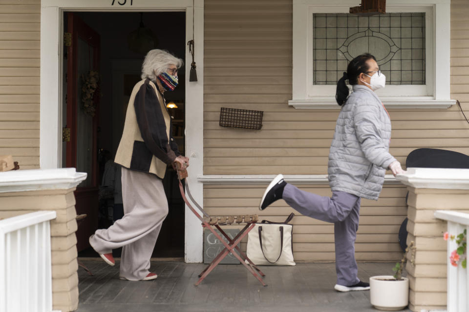 Designer Gere Kavanaugh, left, wears a face mask of her design, as she exercises with Silver Age Home Health licensed vocational nurse Daisy Cabaluna during a weekly outdoors session at her home in the Echo Park neighborhood of Los Angeles, Monday, May 17, 2021. California is keeping its rules for wearing face masks in place until the state more broadly lifts its pandemic restrictions on June 15. (AP Photo/Damian Dovarganes)