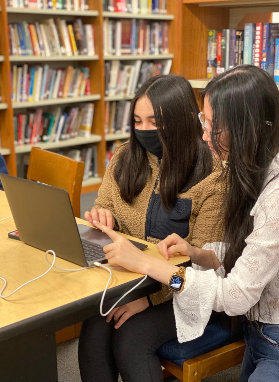 Nora Sun (right), 17, helps a student participant in one of the nonprofits she founded to advocate for girls pursuing studies or careers in science, technology, engineering or mathematics.