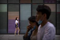People wearing face masks to protect against the new coronavirus walk through an outdoor shopping mall in Beijing, Saturday, July 4, 2020. China reported a single new case of coronavirus in Beijing on Saturday, plus a few more cases elsewhere believed to have come from abroad. (AP Photo/Mark Schiefelbein)