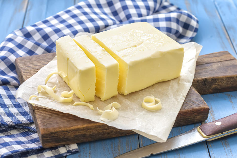 a stick of butter sliced into 3 on a wooden cutting board