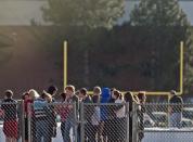 Students gather outside Arapahoe High School, after a student opened fire in the school in Centennial, Colorado December 13, 2013. The student seeking to confront one of his teachers opened fire at the Colorado high school on Friday, wounding at least two classmates before apparently taking his own life, law enforcement officials said. REUTERS/Evan Semon (UNITED STATES - Tags: EDUCATION CRIME LAW)