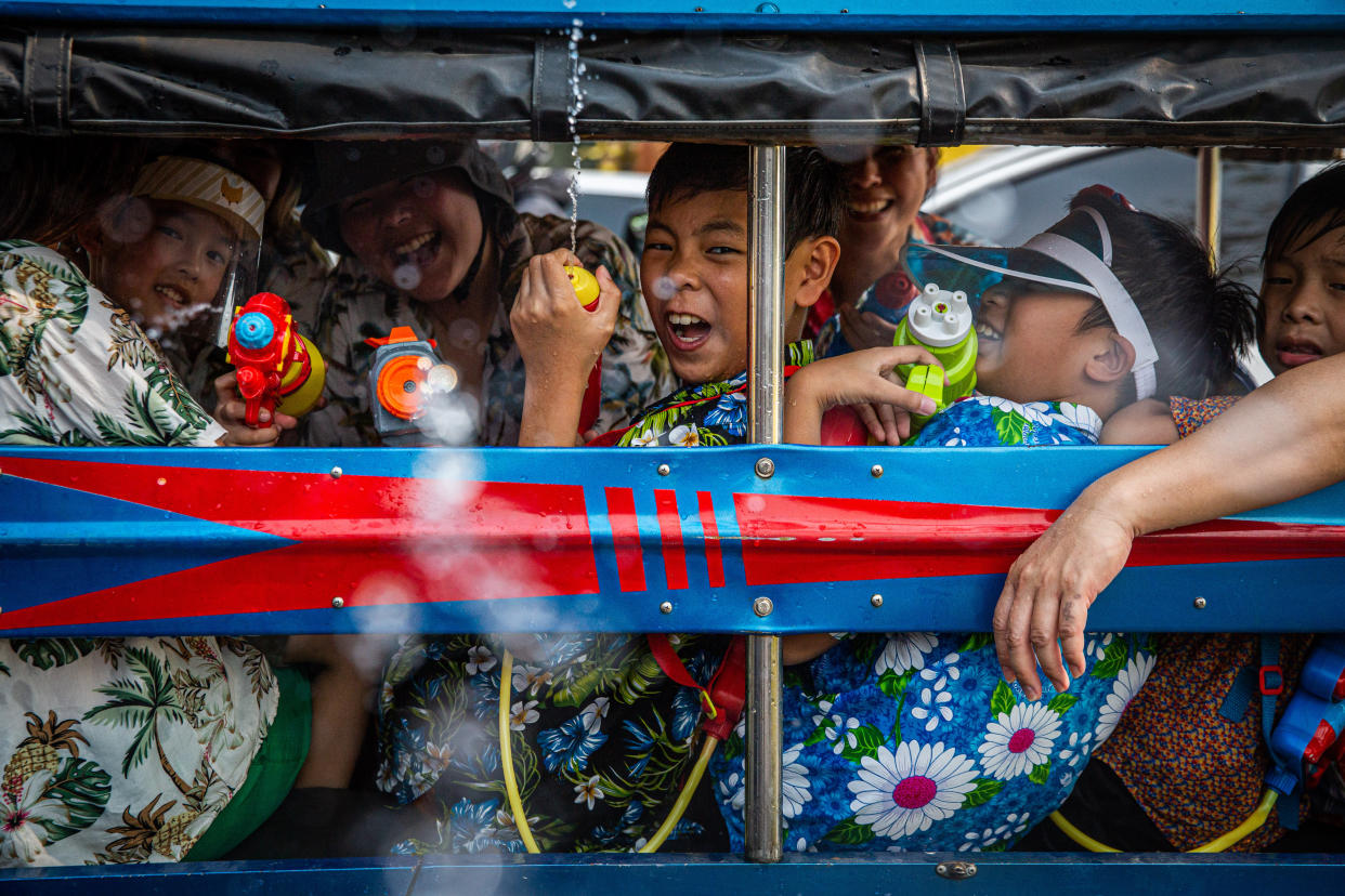 Songkran revelers spray water guns out of a traditional Thai truck 