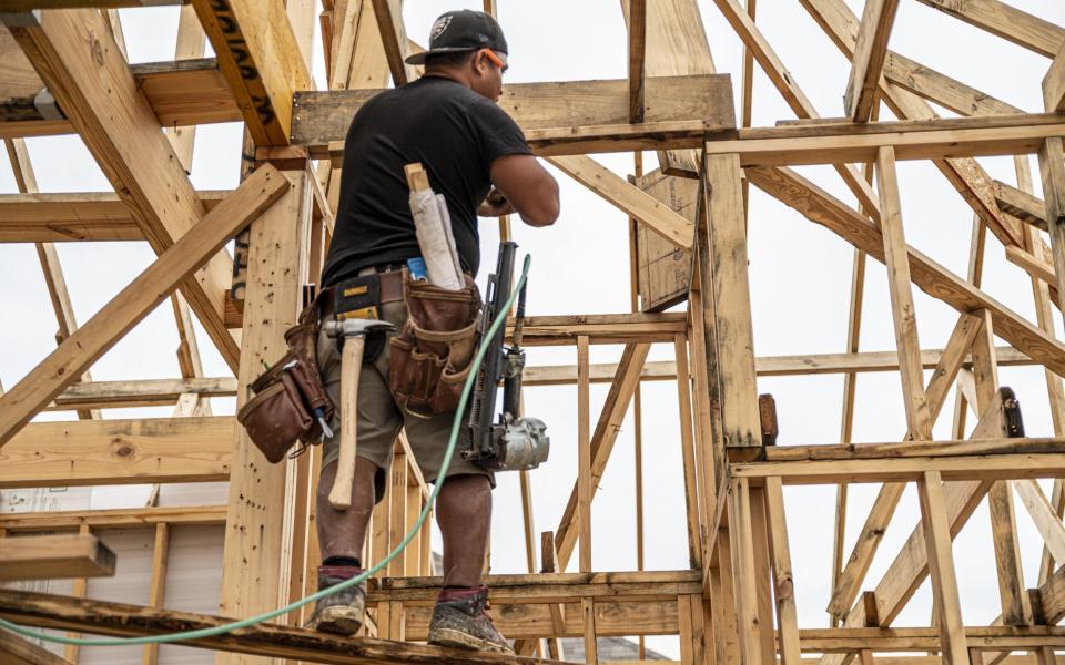 A worker installs wood on a building site in Texas