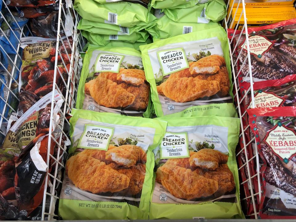 Bags of frozen Trader Joe's chicken in the freezer. In the middle are green bags of Trader Joe's breaded chicken tenderloin breasts.