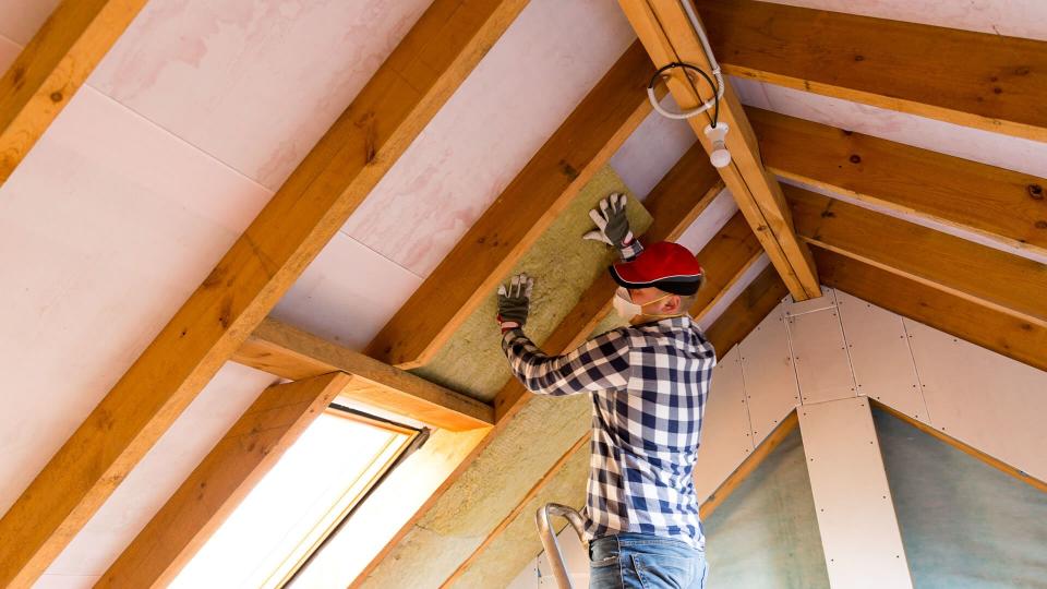 Man installing thermal roof insulation layer - using mineral wool panels.