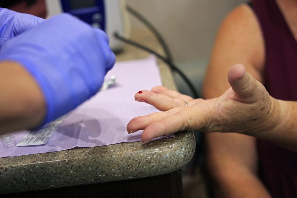 Victoria Nelson has her finger pricked by registered nurse Claudia Portell during a checkup inside Ascension St. Vincent's mobile health care clinic at Lakeshore Baptist Church in Jacksonville.