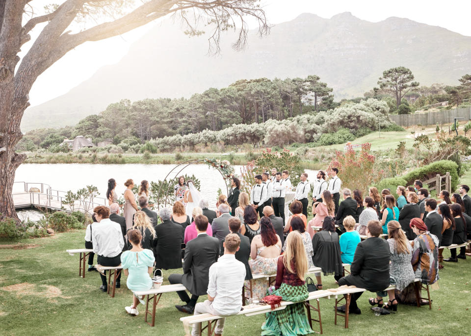 Outdoor wedding ceremony with seated guests and the couple at the altar, mountain backdrop