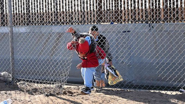 PHOTO: A family of migrants from Colombia climbs through a canal fence after crossing under a hole in the US-Mexico border wall, Dec. 19, 2022, in El Paso, Texas. (Patrick T. Fallon/AFP via Getty Images)