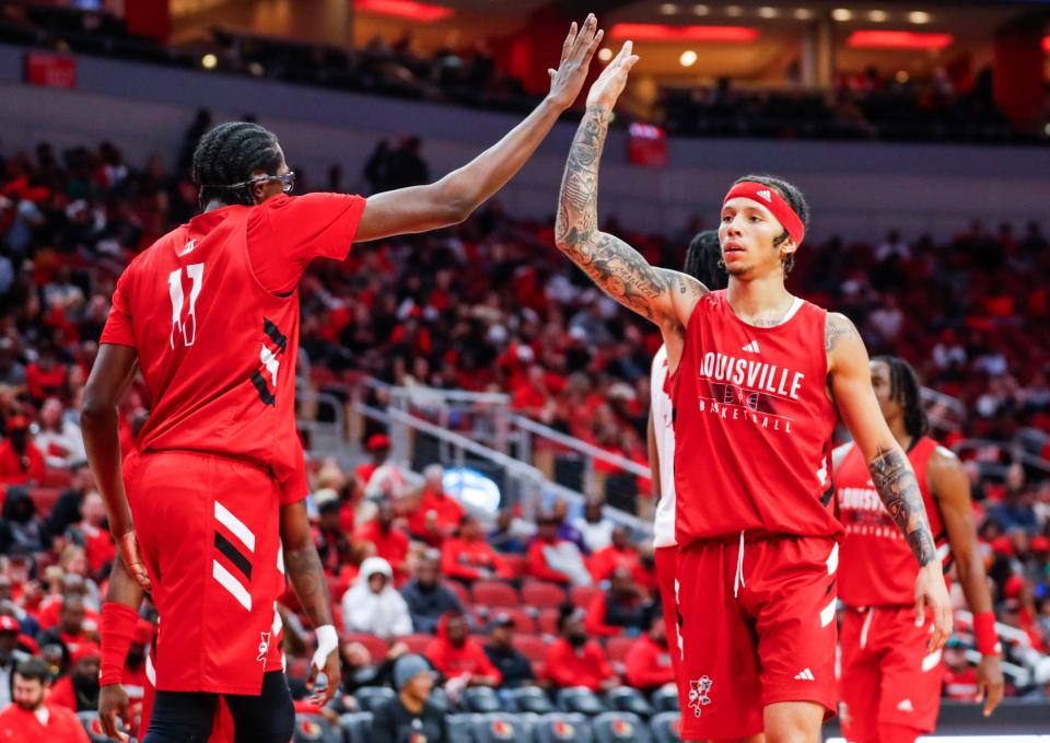 Louisville guard Tre White, right, gives a high five to seven-footer teammate Dennis Evans, left, at the Red-White scrimmage game at the KFC Yum! Center Oct. 11, 2023.
