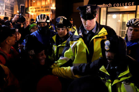 Police officers react as demonstrators against U.S. President-elect Donald Trump knock a police motorcycle on its side outside the National Press Building while the Deploraball is underway in Washington, U.S., January 19, 2017. REUTERS/James Lawler Duggan