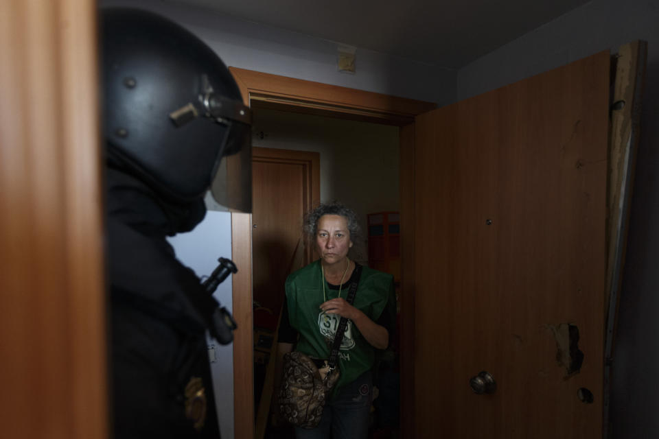 A police officer in full riot gear talks to Veronica Carro, 51 years old, born in Argentina and with Spanish citizenship during her eviction, in Parla, Spain, Wednesday, April 30, 2014. Veronica, a former gardener and concierge at Parla's townhall, has resided in the apartment with her 14 year old daughter Rocio for the past 5 years, but since being unemployed for the last 3 years and her only income was a state handout of 426 euros ($584) a month she could not afford to pay a protected rent of 370 euros a month ($513) to Lazora, a private investor company who bought her house from the City Hall Housing and Land Company (EMVS). Lazora demanded their eviction. (AP Photo/Daniel Ochoa de Olza)