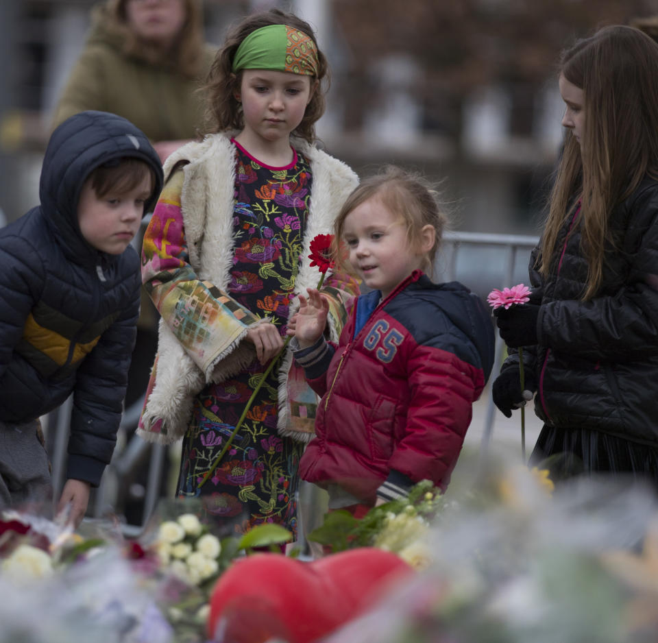 Children lay flowers at a makeshift memorial site for the victims of a shooting incident in a tram in Utrecht, Netherlands, Tuesday, March 19, 2019. A gunman killed three people and wounded others on a tram in the central Dutch city of Utrecht Monday March 18, 2019. (AP Photo/Peter Dejong)