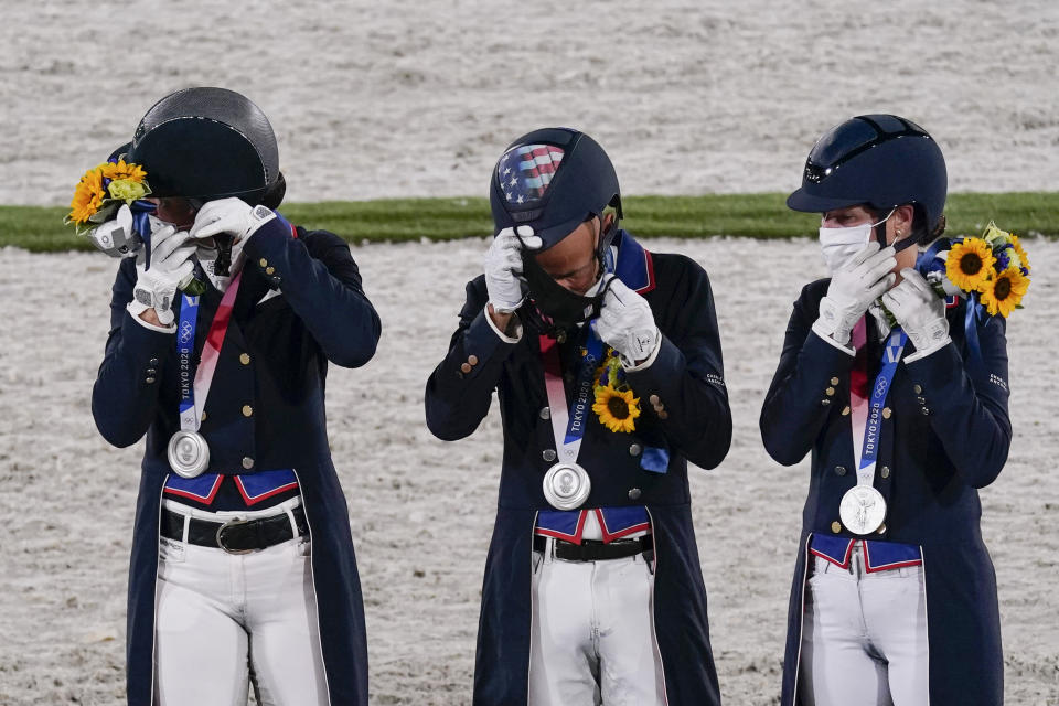 United States' Adrienne Lyle, Steffen Peters, and Sabine Schut-Kery, replace their face masks after photographs as they celebrate their silver medal in the Equestrian Dressage team final at Equestrian Park at Equestrian Park during the 2020 Summer Olympics, Tuesday, July 27, 2021, in Tokyo, Japan. (AP Photo/Carolyn Kaster)