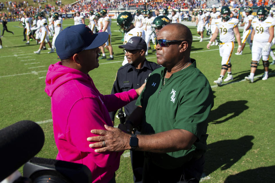 Virginia head coach Tony Elliott, left, shakes hands with William & Mary head coach Mike London, right, after an NCAA college football game Saturday, Oct. 7, 2023, in Charlottesville, Va. (AP Photo/Mike Caudill)