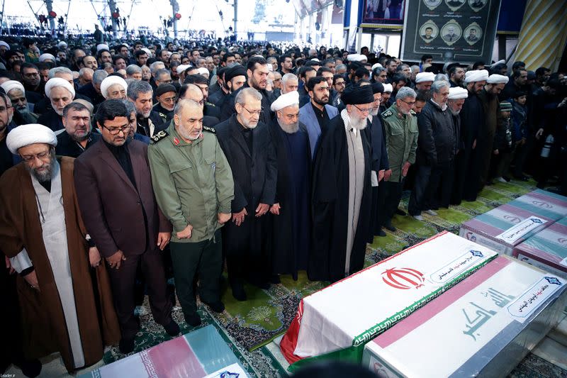 Iran's Supreme Leader Ayatollah Ali Khamenei and Iranian President Hassan Rouhani pray near the coffins of Iranian Major-General Qassem Soleimani, head of the elite Quds Force, and Iraqi militia commander Abu Mahdi al-Muhandis, who were killed in an air st