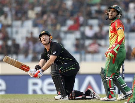 Australia's David Warner (L) plays a ball as Bangladesh's captain and wicketkeeper Mushfiqur Rahim watches during their ICC Twenty20 World Cup match at the Sher-E-Bangla National Cricket Stadium in Dhaka April 1, 2014. REUTERS/Andrew Biraj