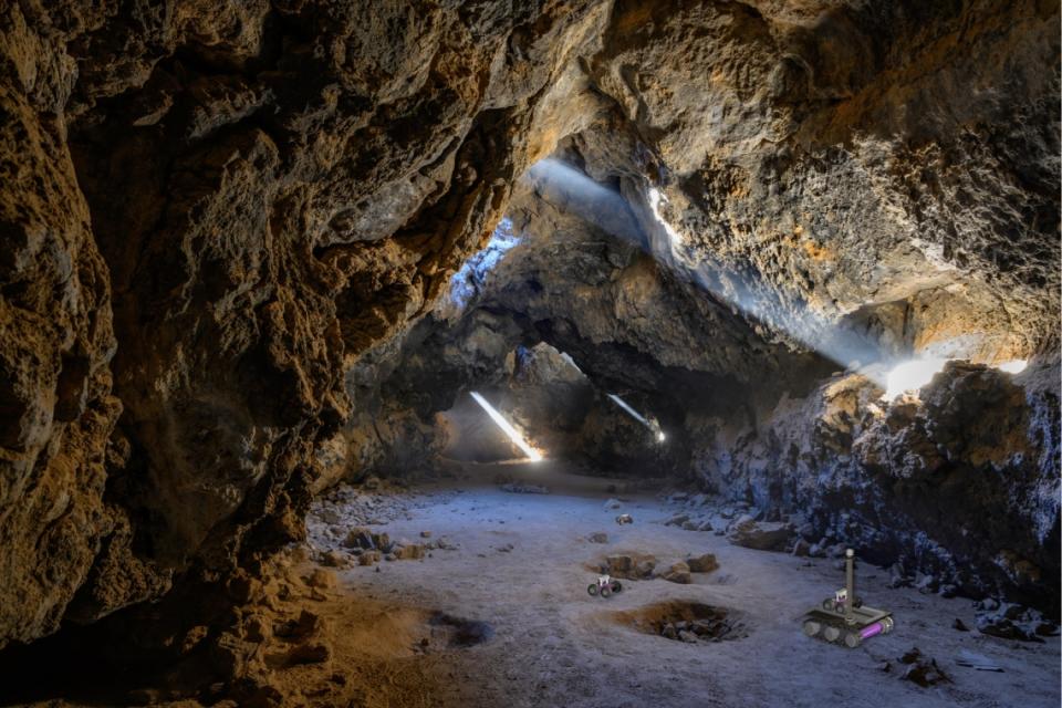  In this artist's impression of the breadcrumb scenario, autonomous rovers can be seen exploring a lava tube after being deployed by a mother rover that remains at the entrance to maintain contact with an orbiter or a blimp. 