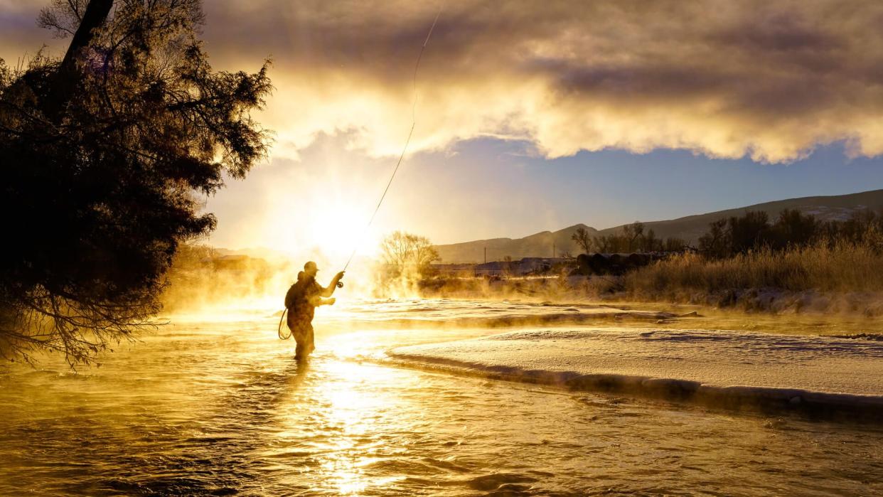 Fly Fishing in Winter at Sunrise - Scenic river with man fishing in cold temperatures.