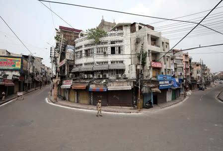 Indian policemen stand guard in a deserted street during restrictions in Jammu