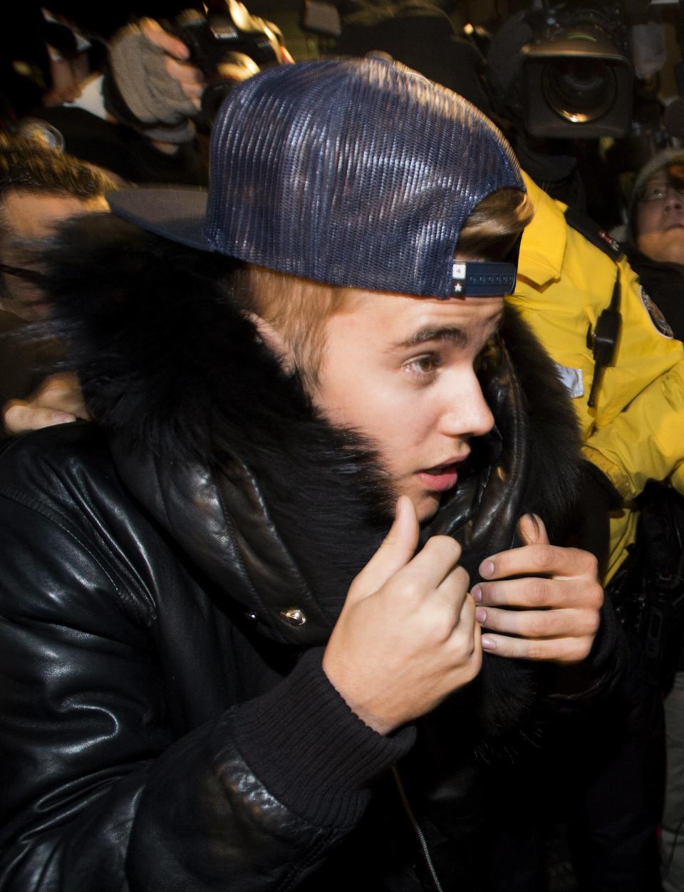 File-This Jan. 29, 2014, file photo shows Canadian musician Justin Bieber being swarmed by media and police officers as he turns himself in to city police for an expected assault charge, in Toronto. Bieber is giving Toronto Mayor Rob Ford a brief respite as Canada's favorite bad boy and butt of all jokes. But the comparison may not be a fair one. The 19-year-old teen idol is facing the equivalent of a misdemeanor assault charge. Ford has admitted smoking crack while in a drunken stupor and is being sued for supposedly orchestrating the jailhouse beating of his sister's ex-boyfriend. (AP Photo/The Canadian Press, Nathan Denette, File)
