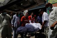 Rescue workers and relatives move a body of a victim, who was killed in a plane crash, in Karachi