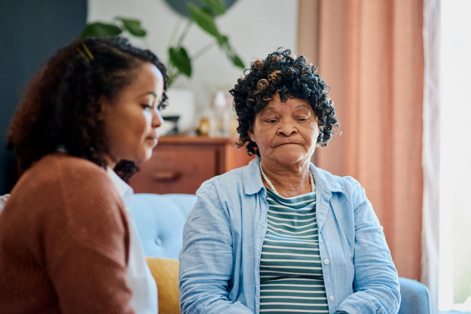 A young woman and an older woman looking solemn on the couch