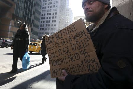 A homeless man sits with a sign on Lexington Avenue in the Manhattan borough of New York, January 4, 2016.REUTERS/Carlo Allegri