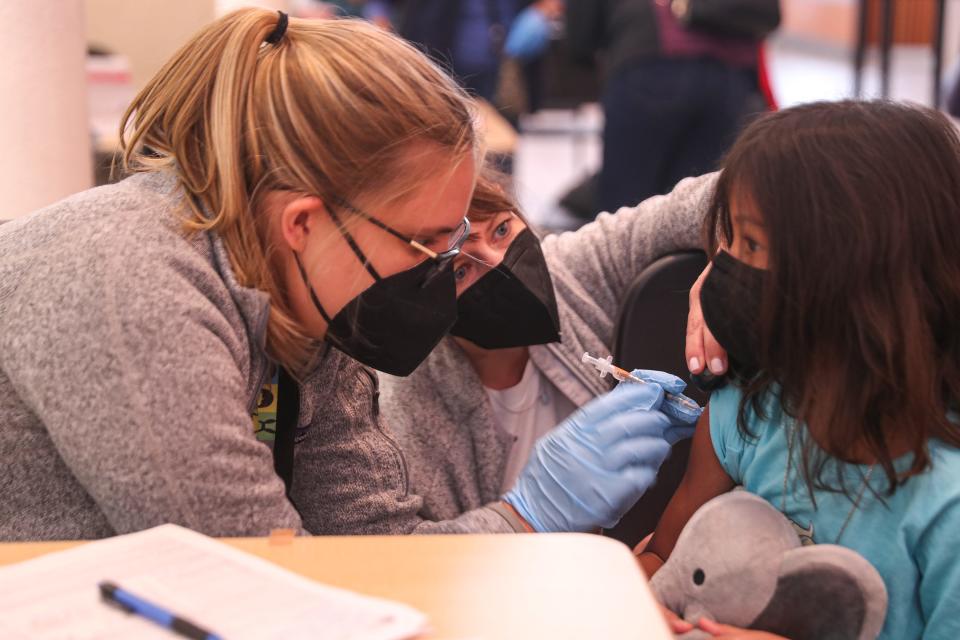 Child life specialist Robyn Moyer, center, calms Isla Soubon, right while Kelsey Fath, left, injects a dose of the Pfizer COVID-19 in January at a clinic by Austin Independent School District and Dell Children's Medical Center. Booster shots for children might be available by Friday.