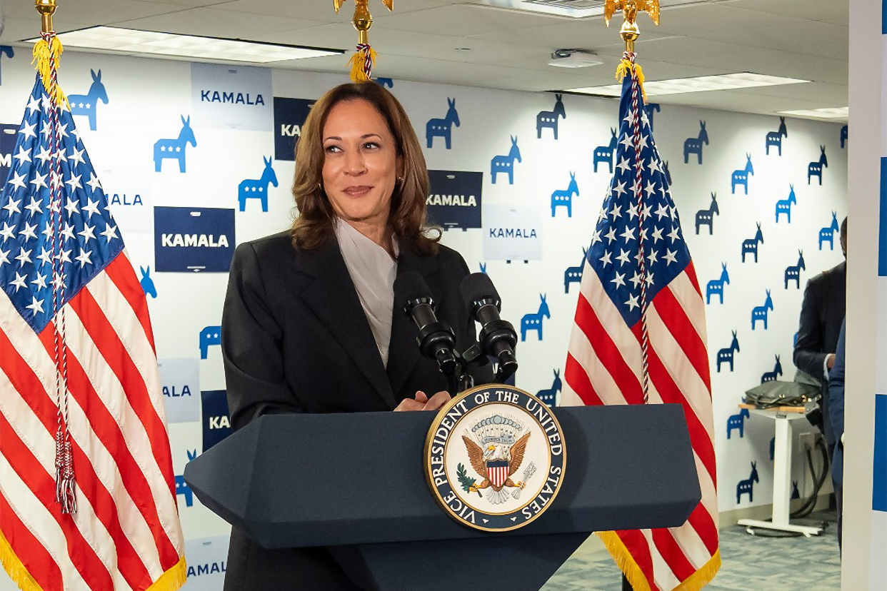 Kamala Harris speaks in front of a background that reads Kamala.