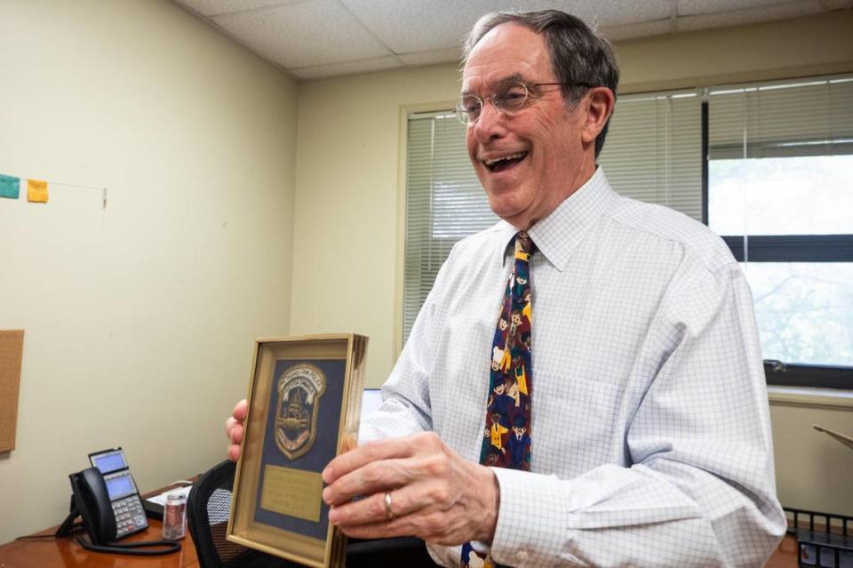 Methodist Justice Ministries founder Brooks Harrington holds up a memento from his career on Wednesday, June 5, at the Methodist Justice Ministry offices in downtown Fort Worth. Harrington is retiring from the organization after 18 years of service.