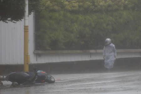 A motorcyclist takes cover from strong winds as Typhoon Megi hits Hualien, eastern Taiwan, September 27, 2016. REUTERS/Tyrone Siu