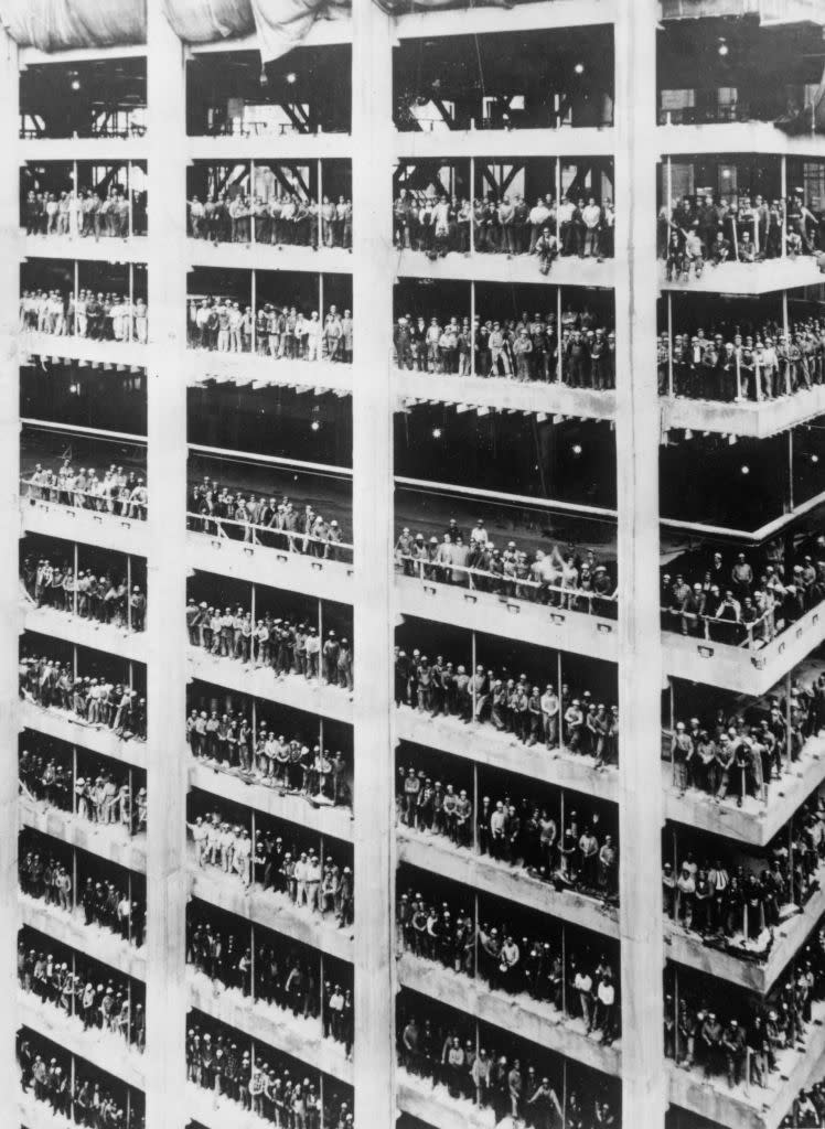 Workers line the decks of a multi-level shipyard during construction