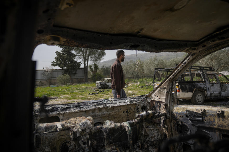 A Palestinian man walks between scorched cars in a scrapyard, in the town of Hawara, near the West Bank city of Nablus, Monday, Feb. 27, 2023. Scores of Israeli settlers went on a violent rampage in the northern West Bank, setting cars and homes on fire after two settlers were killed by a Palestinian gunman. Palestinian officials say one man was killed and four others were badly wounded. (AP Photo/Ohad Zwigenberg)