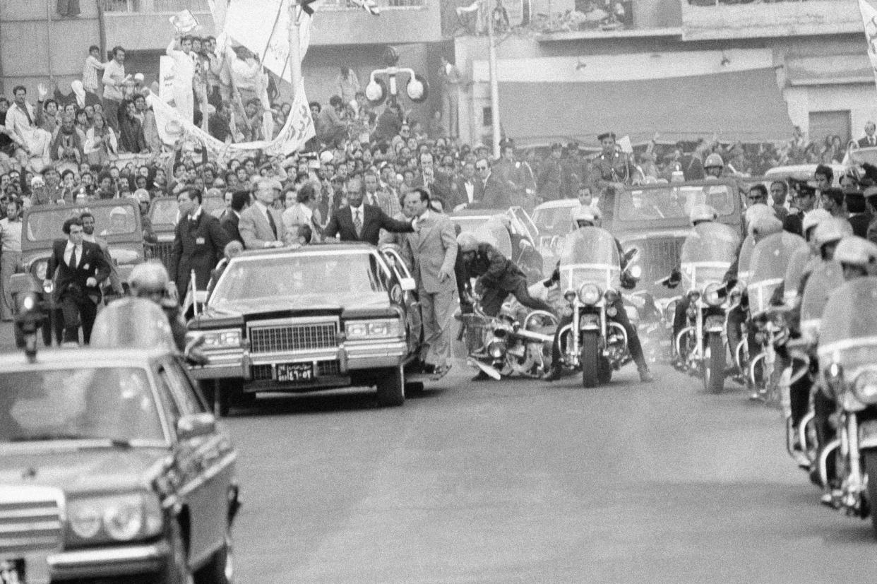 A motorcycle policeman falls while trying to avoid a man rushing to the car with President Jimmy Carter and Egyptian President Anwar Sadat on March 8, 1979, in Cairo.