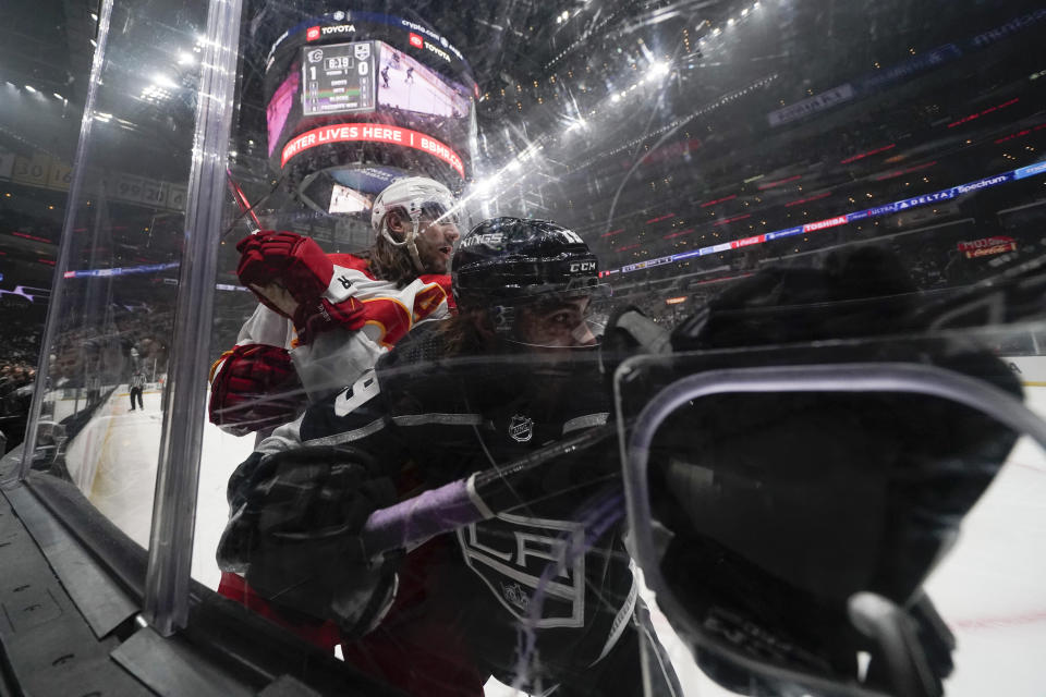 Los Angeles Kings left wing Alex Iafallo, right, and Calgary Flames defenseman Chris Tanev hit the glass during the first period of an NHL hockey game Thursday, Dec. 22, 2022, in Los Angeles. (AP Photo/Ashley Landis)