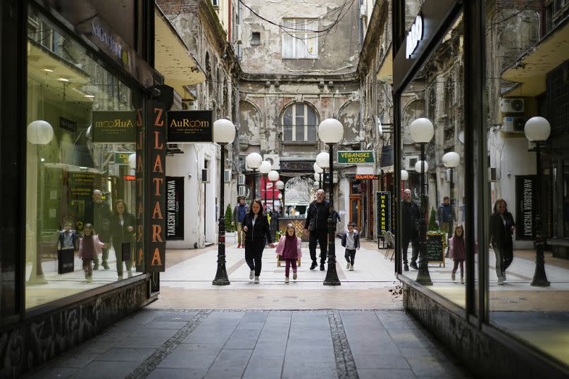 FILE: People with children walk in a street in Belgrade, Serbia, Wednesday, March 8, 2023