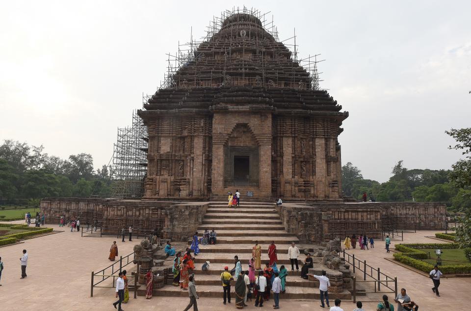 Tourists visits the Konark Sun temple in Konark, in eastern Orissa state on December 12, 2014. The Konark Sun Temple is a 13th-century Sun Temple built by King Narasimhadeva I of the Eastern Ganga Dynasty around 1250. The temple, a UNESCO World Heritage Site, has been built in the shape of a gigantic chariot with elaborately carved stone wheels, pillars and walls and a major part of the structure is now in ruins.   AFP PHOTO/ Prakash SINGH        (Photo credit should read PRAKASH SINGH/AFP/Getty Images)