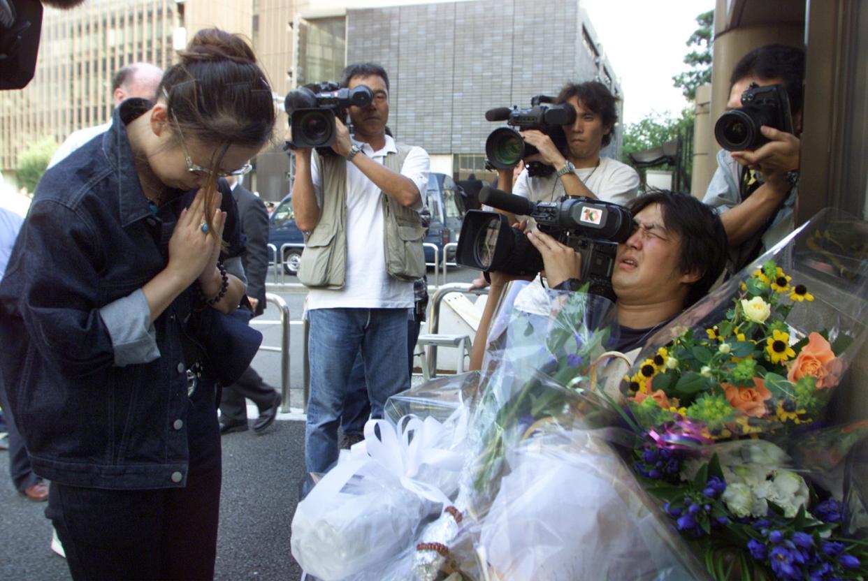 A Japanese woman offers a prayer for victims of terrorist attacks on New York and Washington after laying flowers at the U.S. Embassy in Tokyo September 12, 2001. A shocked United States shut embassies across Asia and put its forces on maximum alert on Wednesday as the region braced for more fallout from the extraordinary airplane attacks on New York and Washington.