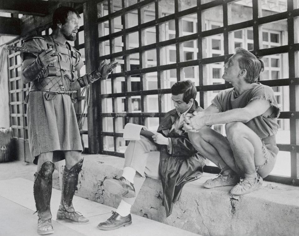 Director Stanley Kubrick makes notes on his script while Charles McGraw (L) and Kirk Douglas (R) discuss a forthcoming scene  - Bettmann