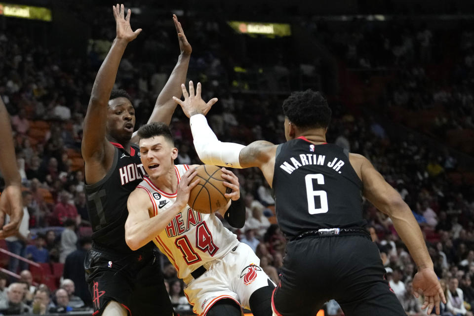 Miami Heat guard Tyler Herro (14) drives to the basket as Houston Rockets forward Jae'Sean Tate, left, and forward Kenyon Martin Jr. (6) defend during the second half of an NBA basketball game Friday, Feb. 10, 2023, in Miami. (AP Photo/Lynne Sladky)