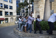 Civilians who had been hiding in buildings flee under the direction of security forces at a hotel complex in Nairobi, Kenya Tuesday, Jan. 15, 2019. Terrorists attacked an upscale hotel complex in Kenya's capital Tuesday, sending people fleeing in panic as explosions and heavy gunfire reverberated through the neighborhood. (AP Photo/Ben Curtis)