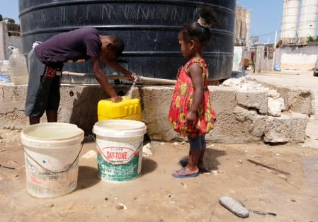 Libyan children displaced from the town of Tawergha fill containers with water at a displaced camp in Benghazi