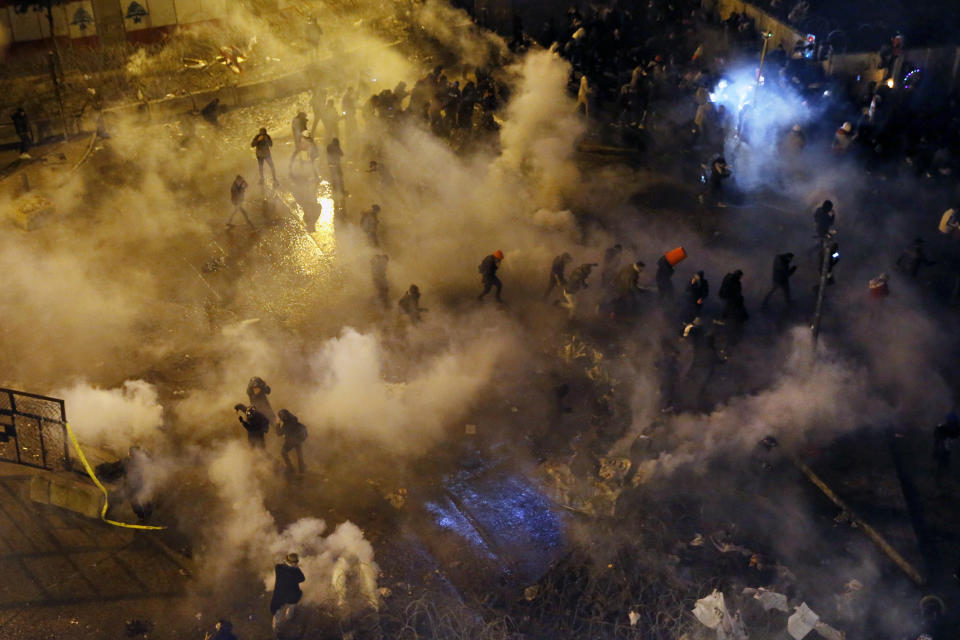 Riot police fire tear gas against anti-government protesters as they try to cross to the central government building during ongoing protests in Beirut, Lebanon, Saturday, Jan. 25, 2020. Hundreds of Lebanese gathered outside the central government building to reject the newly formed Cabinet, while some protesters breached tight security erected around it, removing a metal gate and barbed wire prompting a stream of water cannons from security forces. (AP Photo/Bilal Hussein)