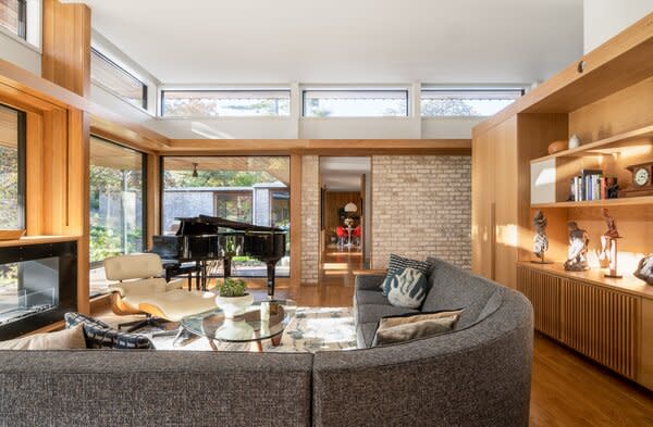 The living room has a pavilion-like feel, featuring a grand piano, upholstered sectional, Eames lounge chair and ottoman, and Isamu Noguchi coffee table, but no visible television.