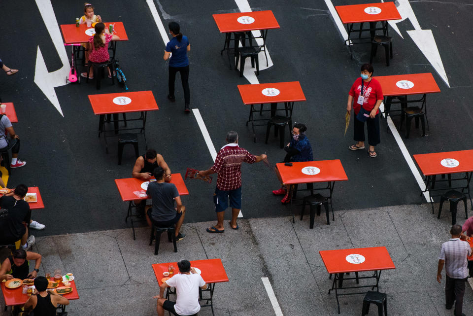 People seated in groups of 2 as mandated by Covid-19 safety restrictions are served by staff as they dine at a food centre  in Singapore on Saturday, 23 October, 2021. (Photo by Joseph Nair/NurPhoto via Getty Images)