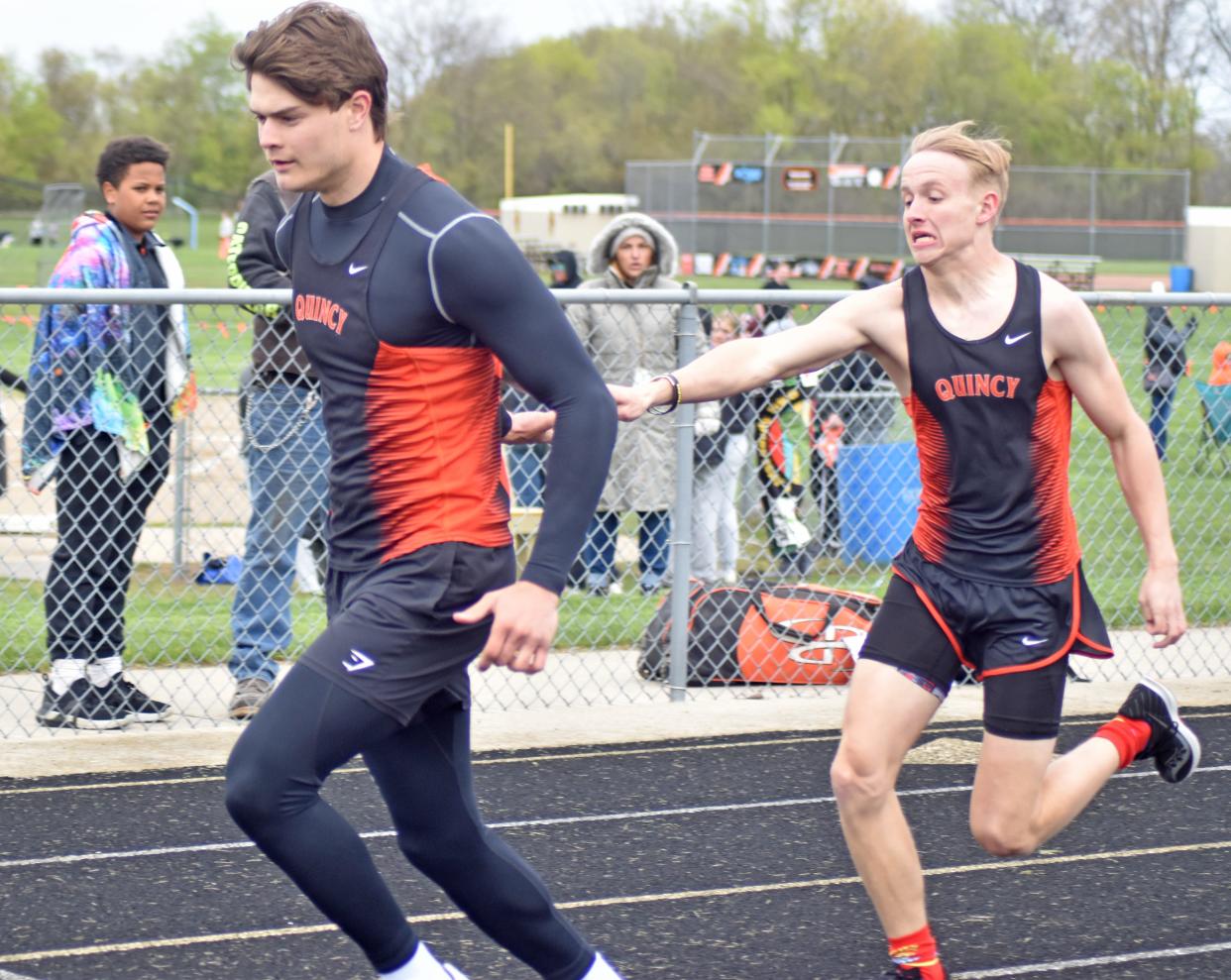 Quincy's Cameron Barry hands off to teammate Noah Rufenacht during the 800 meter relay
